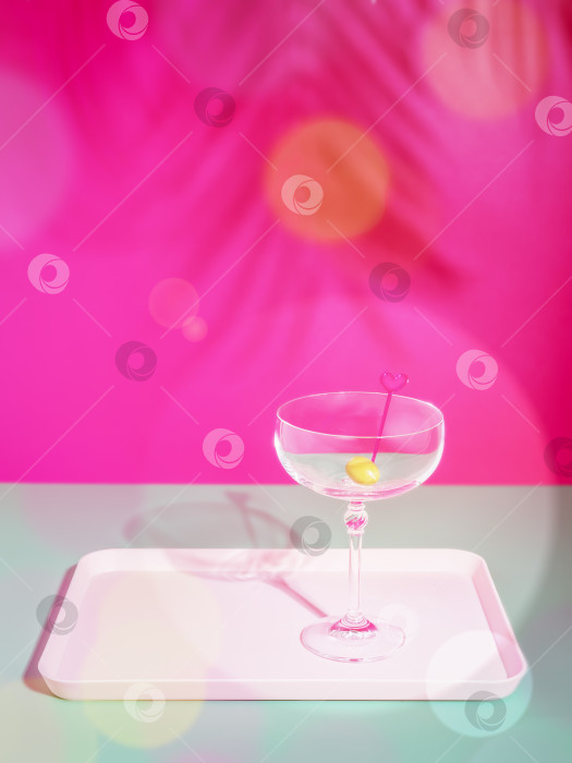 Скачать Пустой бокал для коктейля на подносе на розовом фоне в тени пальмы фотосток Ozero