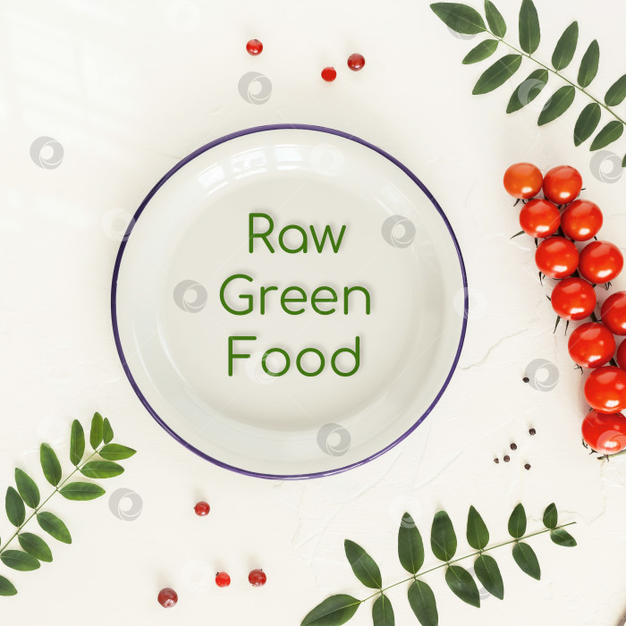 Скачать Пустая белая тарелка с надписью raw green food, помидоры, зелень и специи на белом столе фотосток Ozero