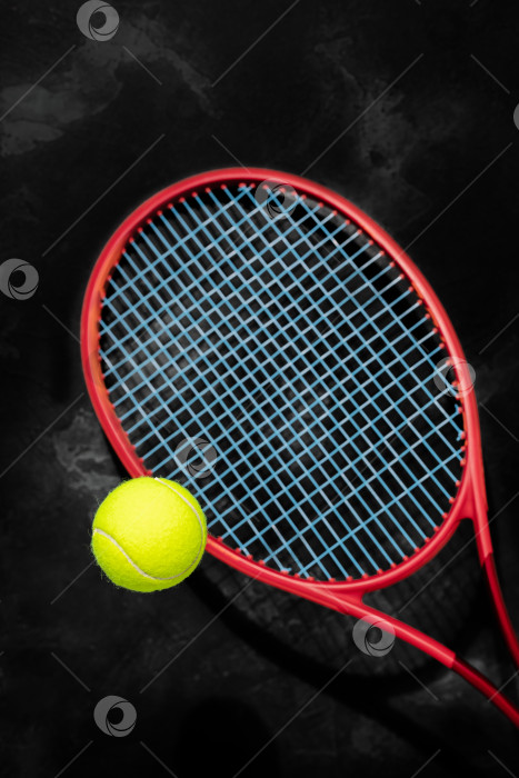 Скачать Желтый теннисный мяч с красной ракеткой на черном фоне фотосток Ozero