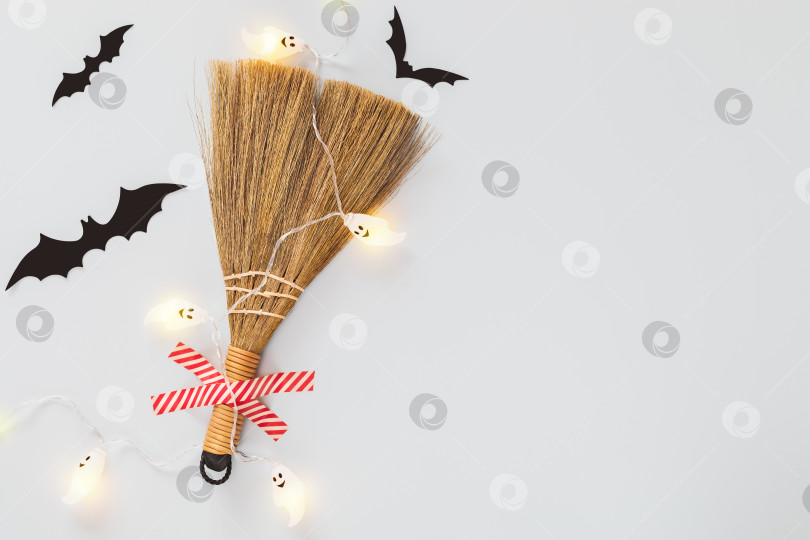 Скачать Хеллоуинская композиция с лентопротяжной метлой, черными летучими мышами и световой гирляндой с привидениями и пространством для копирования фотосток Ozero