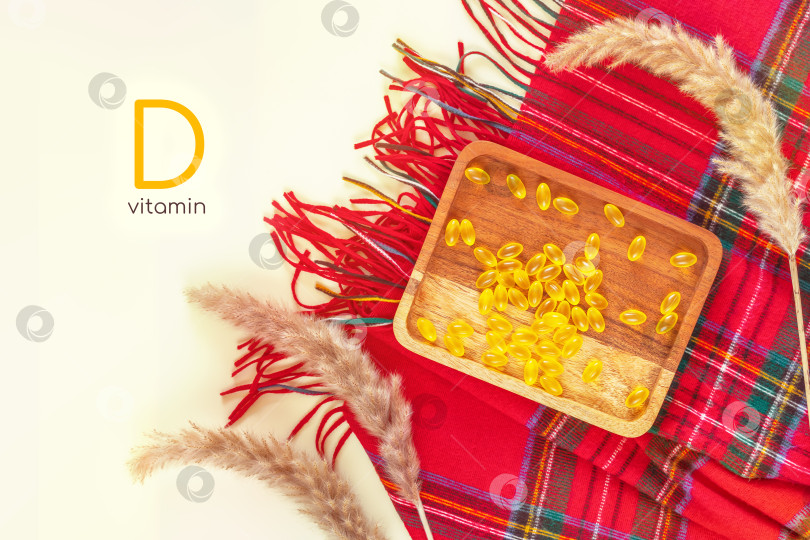 Скачать Деревянная тарелка с желтыми капсулами витаминного геля, красным кашемировым палантином и сухоцветами на белом фоне фотосток Ozero