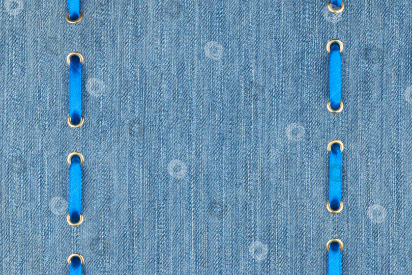 Скачать Голубая атласная лента, вставленная в золотые кольца на джинсовой ткани фотосток Ozero