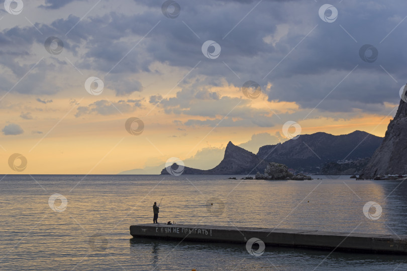 Скачать Одинокий рыбак на волнорезе. фотосток Ozero