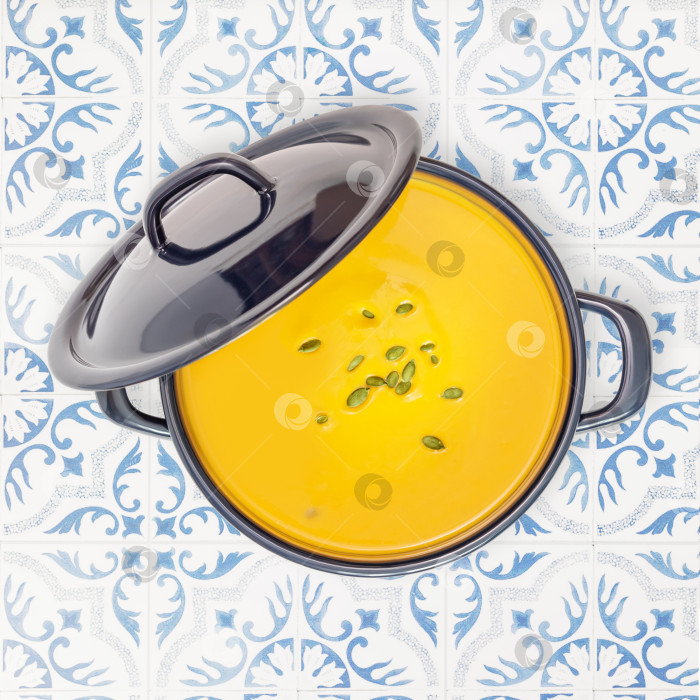 Скачать Тыквенный суп с семечками в кастрюле на фоне плитки фотосток Ozero
