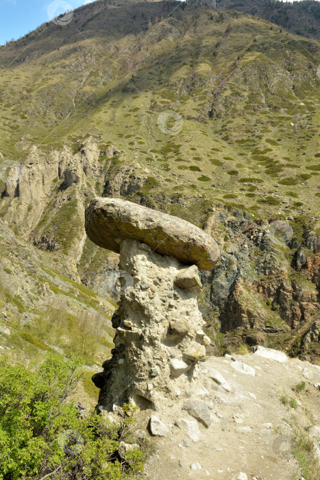 Скачать Огромный камень на тонкой ножке из песчаника на склоне высокой горы в солнечный весенний день. фотосток Ozero