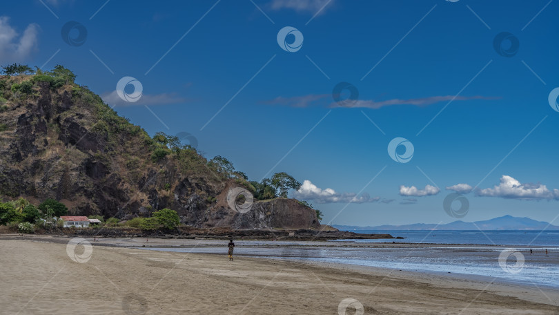 Скачать Женщина прогуливается по берегу океана по песчаному пляжу во время отлива. фотосток Ozero