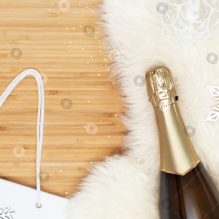 Скачать Бутылка шампанского на белом меховом коврике с рождественским декором фотосток Ozero