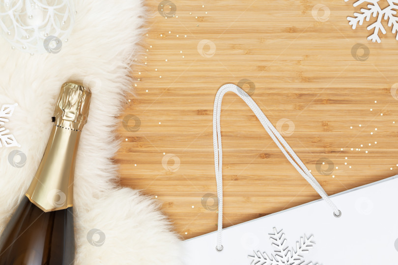 Скачать Бутылка шампанского на белом меховом коврике с белым подарочным пакетом фотосток Ozero