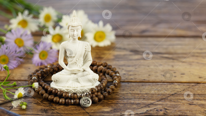 Скачать Статуя Будды, четки и цветы на деревянном фоне фотосток Ozero