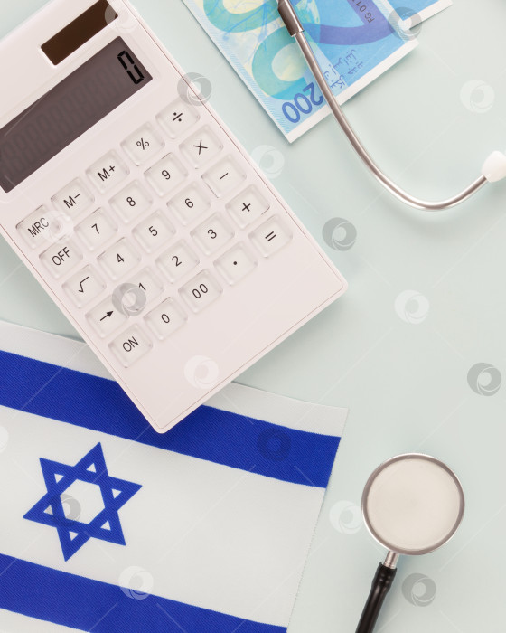 Скачать Калькулятор, стетоскоп, израильский флаг и шекели на синем фоне фотосток Ozero