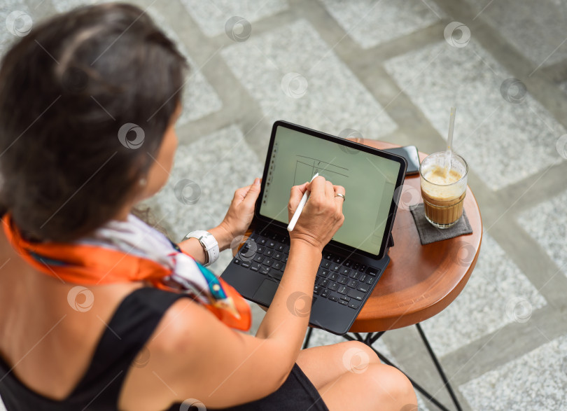 Скачать Молодая женщина занимается финансовым планированием в планшете с помощью стилуса фотосток Ozero