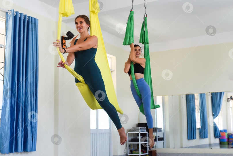 Скачать Инструктор по йоге помогает женщине принять воздушную позу или полетать в йоге фотосток Ozero