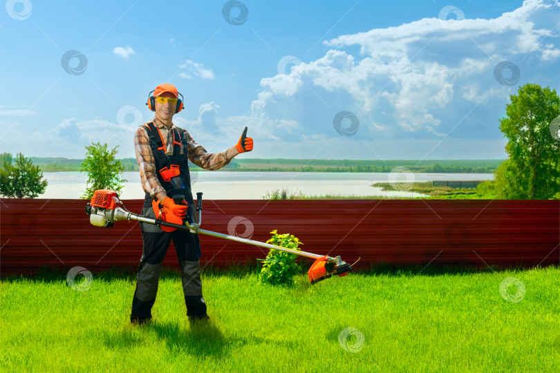 Скачать Портрет счастливого садовода-рабочего с бензиновым триммером, показывающего большой палец вверх. фотосток Ozero