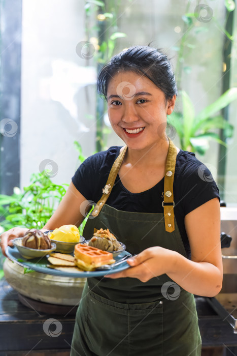 Скачать Вьетнамская девушка подает домашнее мороженое с вафлями в кафе. фотосток Ozero