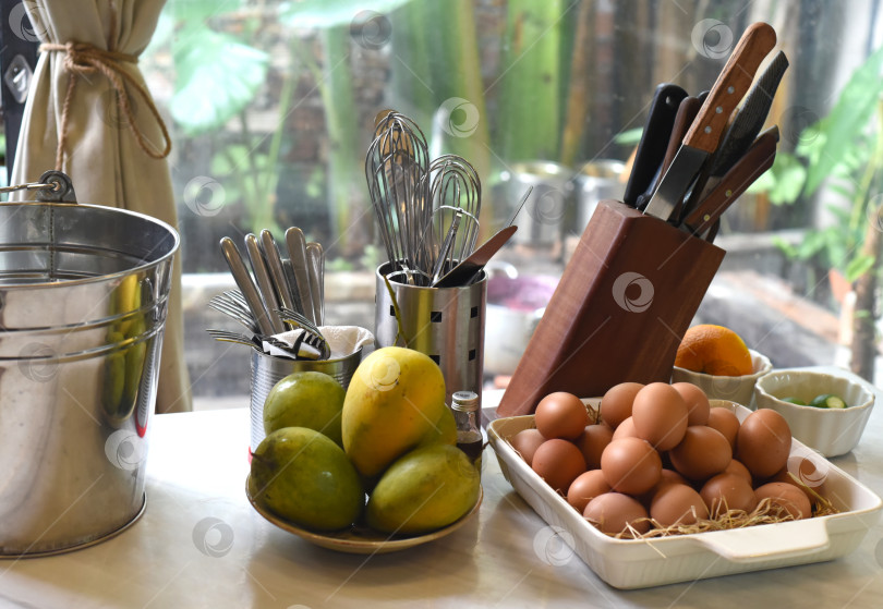 Скачать Кухонные принадлежности с набором ножей и горками яиц и манго на кухне фотосток Ozero