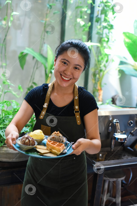 Скачать Вьетнамская девушка подает домашнее мороженое с вафлями в кафе. фотосток Ozero