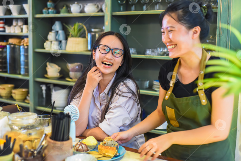 Скачать Улыбчивая вьетнамская официантка подает клиенту мороженое с вафлями во вьетнамской кофейне фотосток Ozero