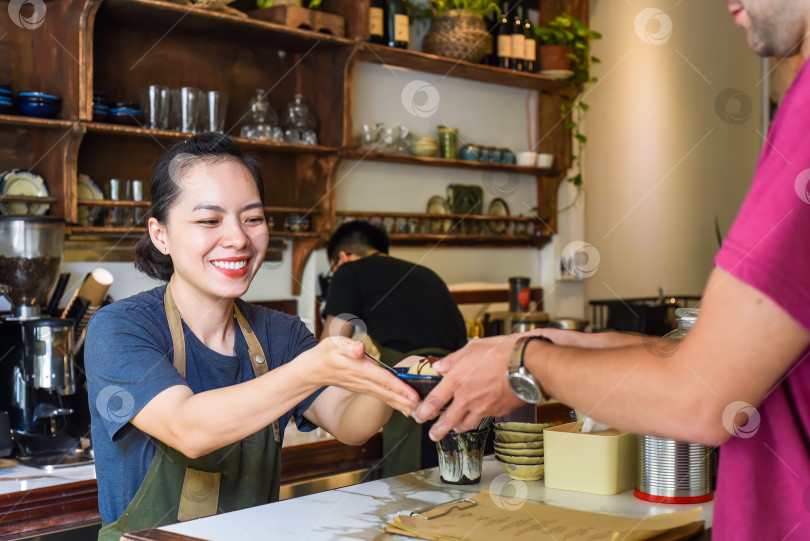 Скачать Вьетнамская официантка подает мороженое посетителю в кофейне фотосток Ozero