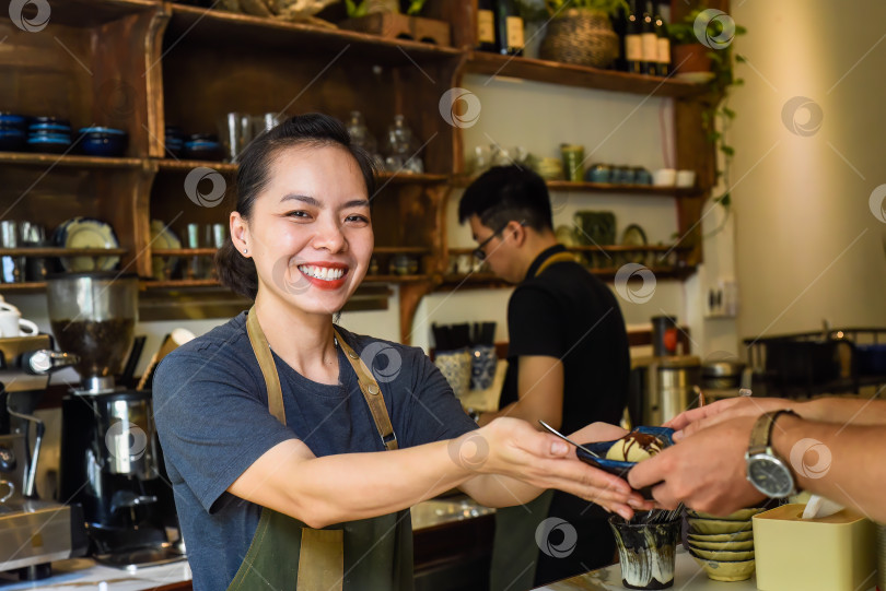 Скачать Вьетнамская официантка подает мороженое клиенту в кофейне фотосток Ozero