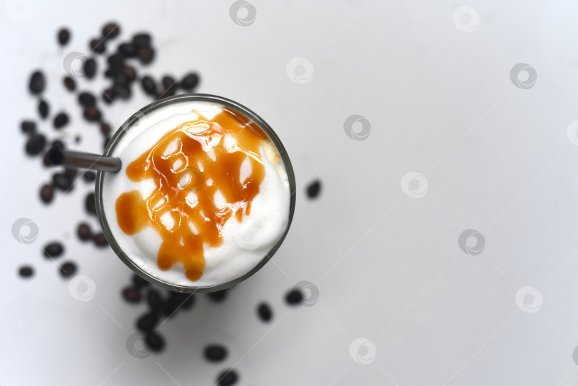 Скачать Латте с ледяной карамелью и кофейными зернами на белом фоне, вид сверху крупным планом фотосток Ozero