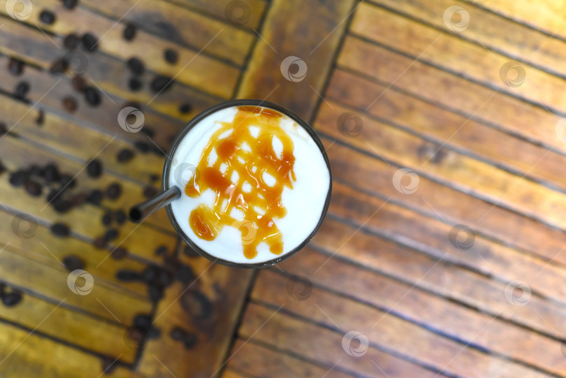 Скачать Латте с ледяной карамелью и кофейными зернами на деревянном столе вид сверху фотосток Ozero