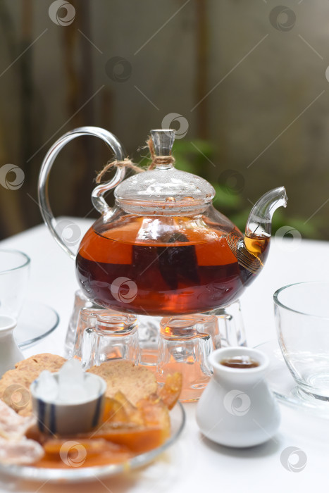 Скачать Чай "Эрл Грей" в стеклянном чайнике с чашками и хрустальными фруктами на деревянном фоне фотосток Ozero