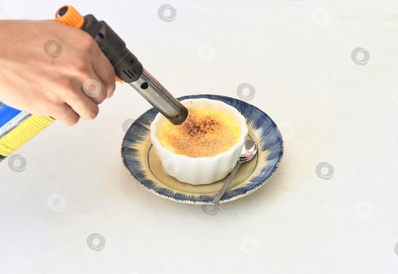 Скачать процесс посыпки крем-брюле коричневым сахаром на белом фоне фотосток Ozero