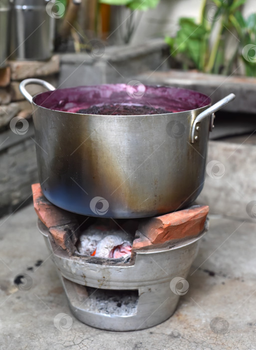 Скачать Варка тутового джема в металлической кастрюле на традиционном вьетнамском глиняном открытом огне фотосток Ozero