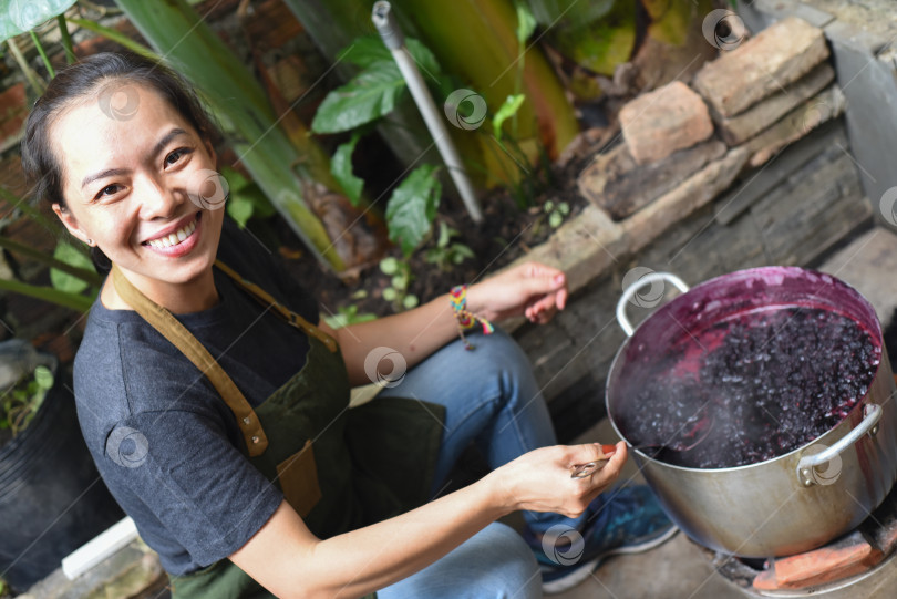 Скачать Молодая вьетнамка готовит тутовый джем в большой кастрюле фотосток Ozero