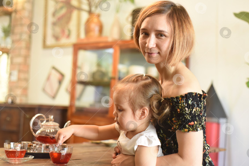 Скачать Молодая женщина с маленькой девочкой пьют чай из чайника в кофейне фотосток Ozero