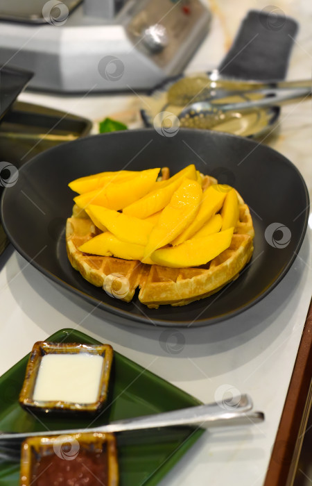 Скачать свежие ломтики манго на запеченных бельгийских вафлях с сиропами фотосток Ozero