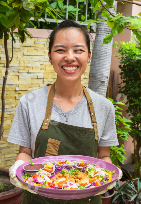 Скачать Вьетнамская женщина-официантка подает жареного цыпленка с овощами в кафе на открытом воздухе фотосток Ozero