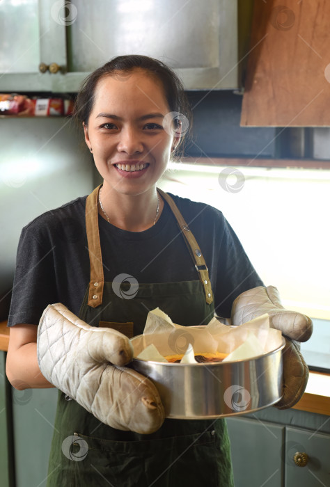 Скачать Вьетнамская женщина держит на кухне форму для выпечки с тестом для чизкейков фотосток Ozero