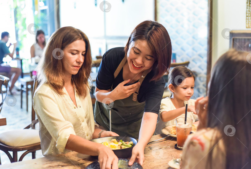 Скачать Вьетнамская официантка убирает со стола для клиентов в кафе, демонстрируя вьетнамскую культуру и вежливость фотосток Ozero