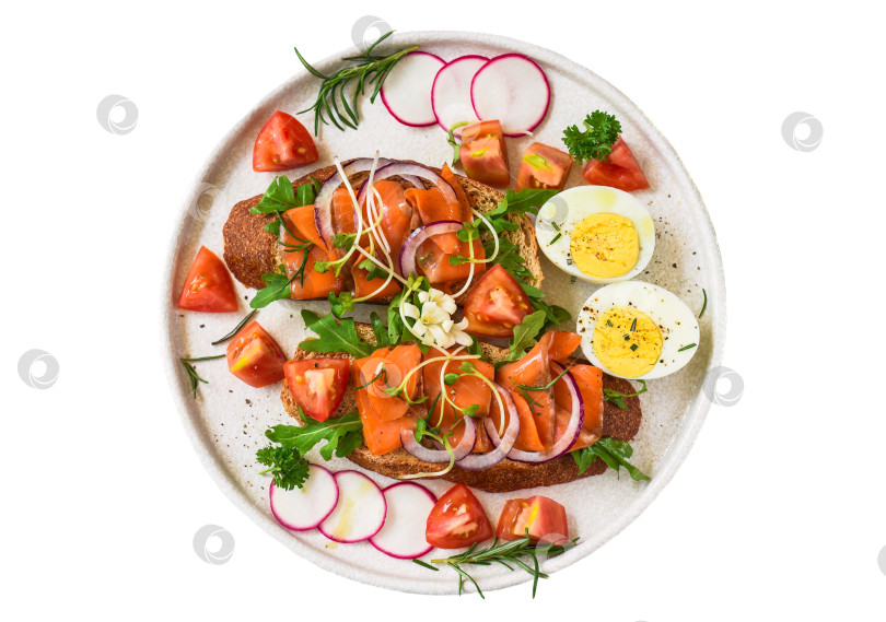 Скачать тосты с копченым лососем, луком и овощами на белой тарелке крупным планом фотосток Ozero