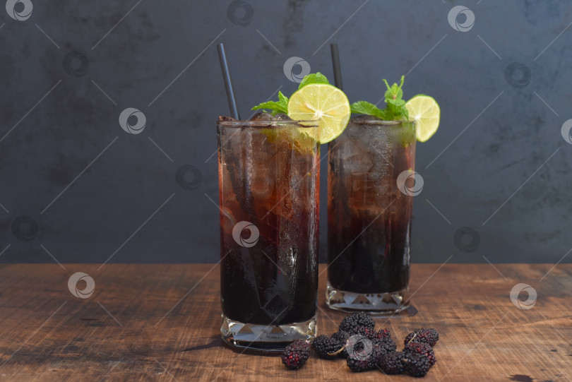 Скачать Два коктейля с шелковичным вином и хайболлом на деревянном столе на черном фоне фотосток Ozero
