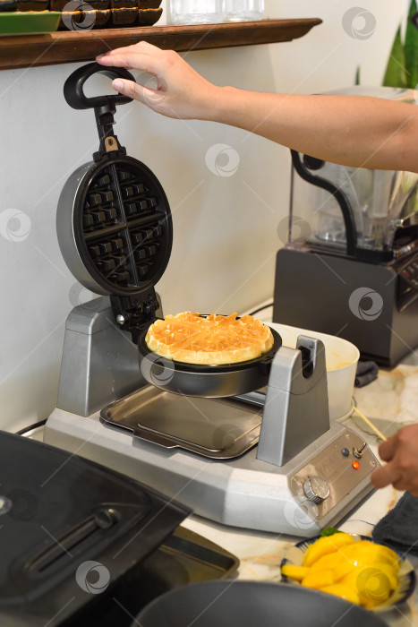 Скачать повар деревянной палочкой выкладывает тесто для сладких вафель в вафельницу фотосток Ozero