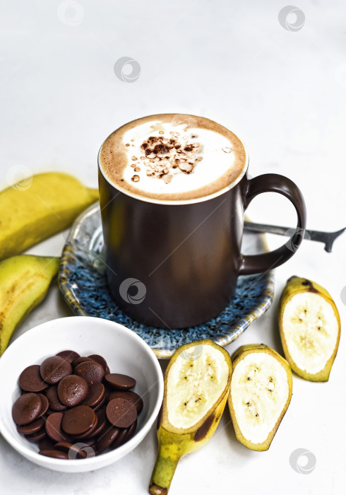 Скачать Бананово-шоколадный латте со свежим бананом и шоколадными каплями на белом столе фотосток Ozero