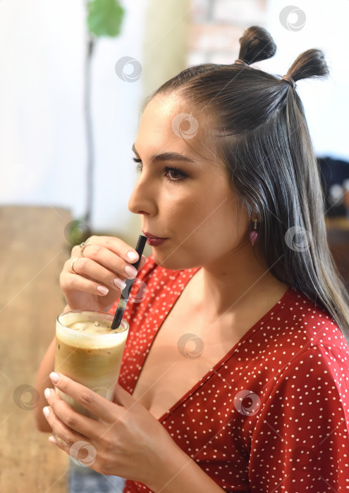 Скачать Молодая женщина пьет кофе со льдом в кофейне фотосток Ozero