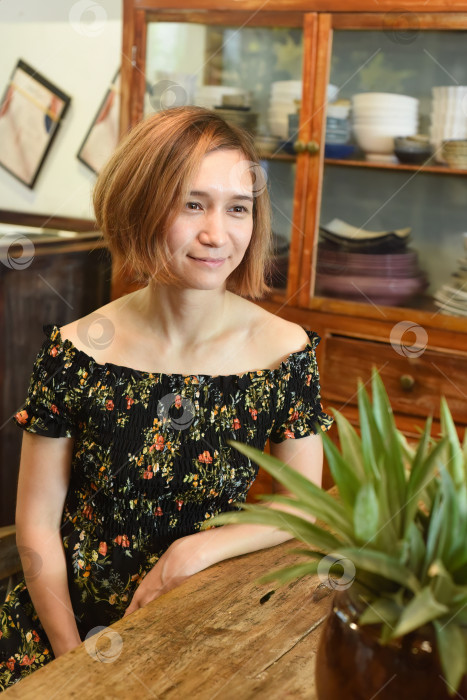 Скачать Молодая женщина сидит за деревянным столом в кофейне фотосток Ozero
