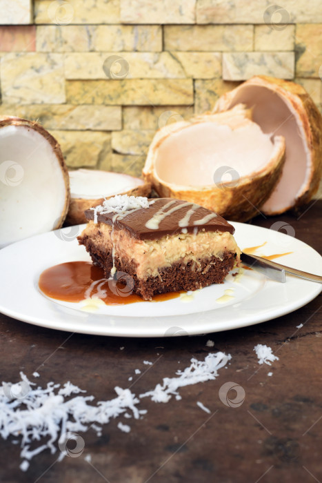 Скачать Кокосовый пирог на белой тарелке с ложкой и карамельным соусом фотосток Ozero
