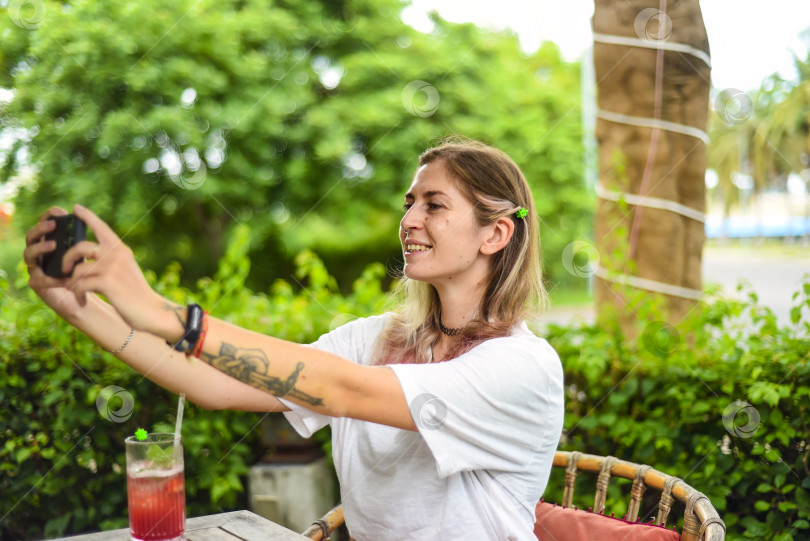 Скачать Симпатичная женщина делает селфи и пьет чай в летнем саду фотосток Ozero