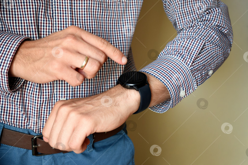 Скачать Мужские руки касаются экрана и используют приложение для своих смарт-часов. Руки крупным планом фотосток Ozero