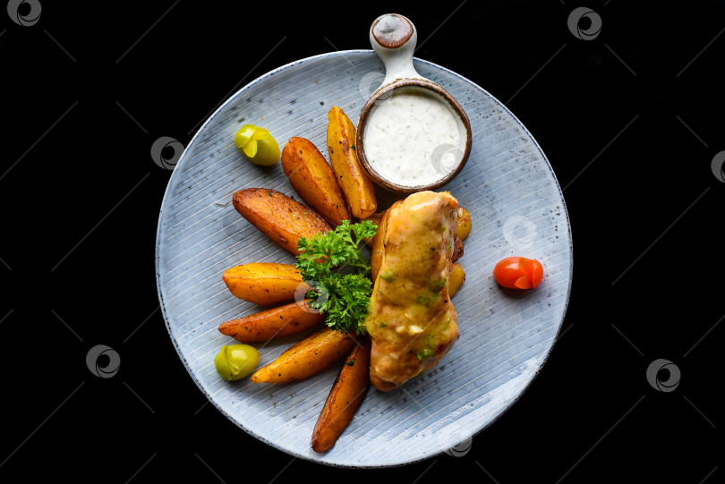 Скачать Стейк из куриной отбивной с картофелем фри на синей тарелке, выделенный на черном фоне, вид сверху фотосток Ozero