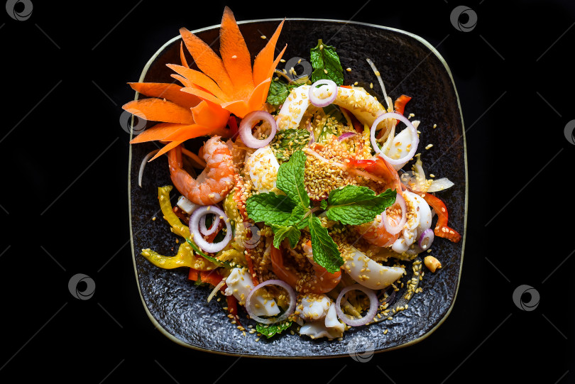 Скачать Тайский салат из креветок, кальмаров и лука на черном фоне, вид сверху фотосток Ozero