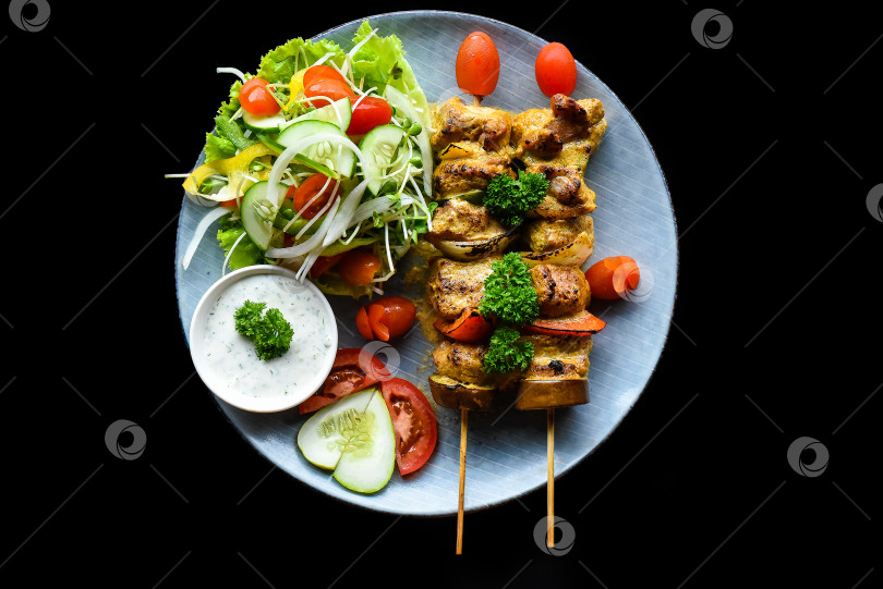 Скачать Шашлык из свинины с овощами гриль, подается с салатом на черном фоне, вид сверху фотосток Ozero