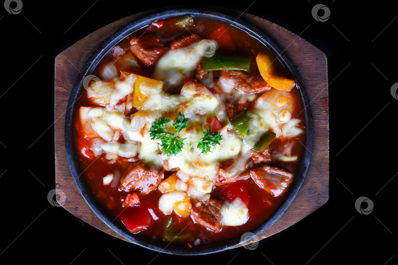 Скачать Тушеная говядина с сыром и овощами на деревянной тарелке на черном фоне, вид сверху фотосток Ozero