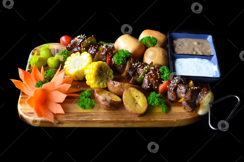 Скачать Шашлык из говядины с перцем и кукурузой подается с вьетнамскими булочками на черном фоне, вид сверху фотосток Ozero