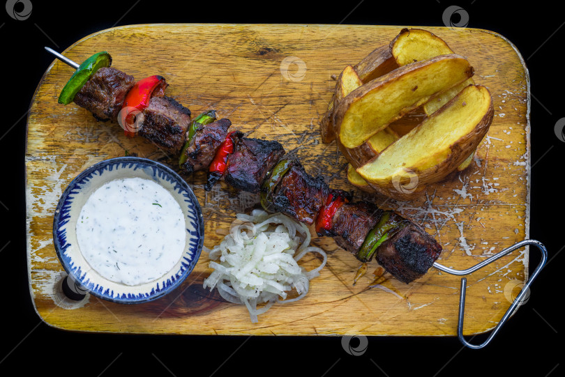 Скачать Шашлык из свинины, подаваемый с салатом и соусом на черном фоне, вид сверху фотосток Ozero