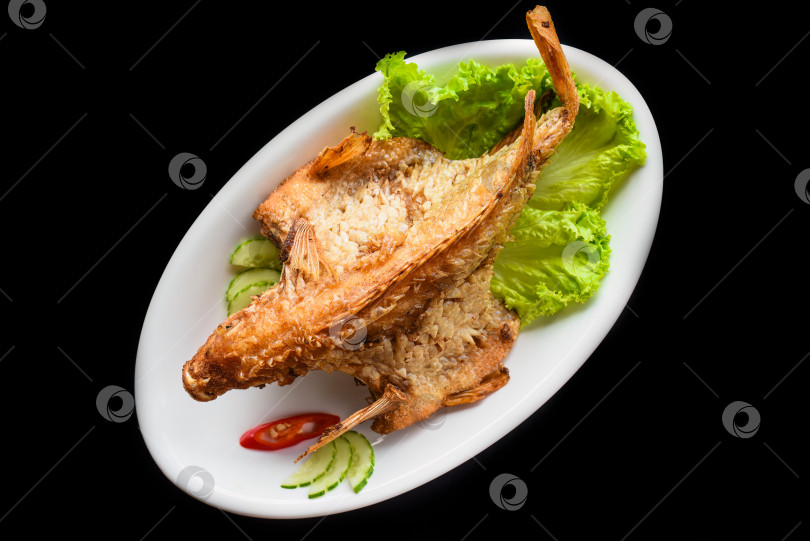 Скачать Рыба, запеченная в кляре с овощами и зеленью на белом блюде на черном фоне, вид сверху фотосток Ozero